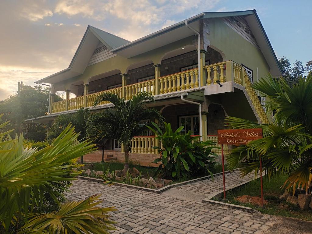 a house with a balcony and a sign in front of it at Bethel's Villas in La Digue