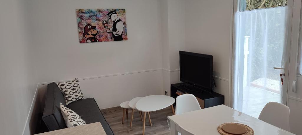 uma sala de estar com um sofá, uma mesa e uma televisão em Ici c'est le Marais Poitevin em Ferrières
