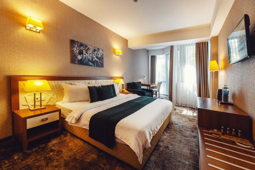 a hotel room with a large bed and a desk at Costé Hotel in Tbilisi City