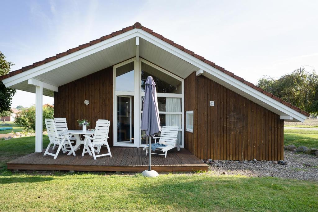 ein Haus mit einem Tisch, Stühlen und einem Sonnenschirm in der Unterkunft Hof Ruhleben Haus Muschelsucher in Pelzerhaken