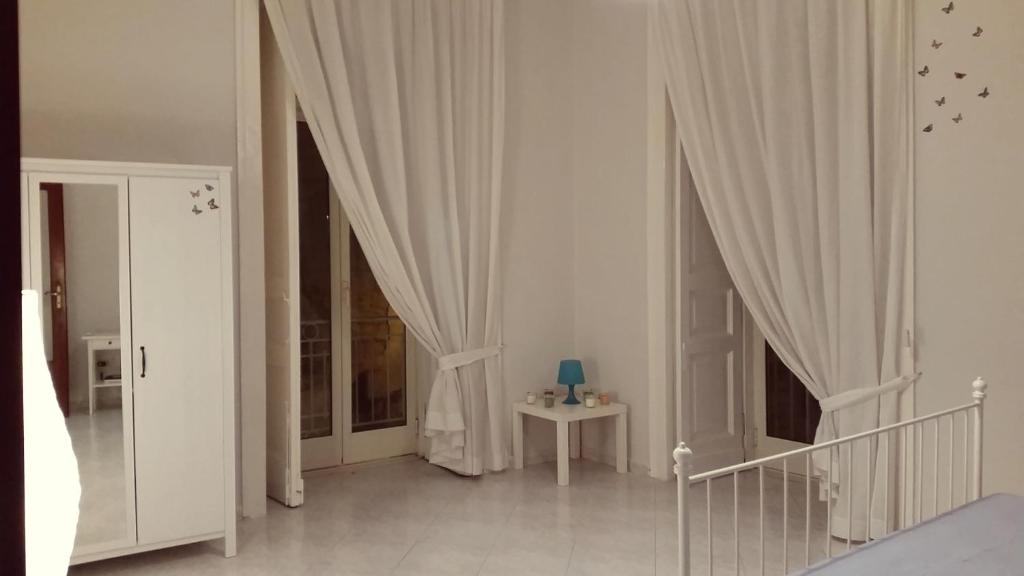 1 dormitorio con cortinas blancas y mesa con lámpara en Napulè, en Nápoles