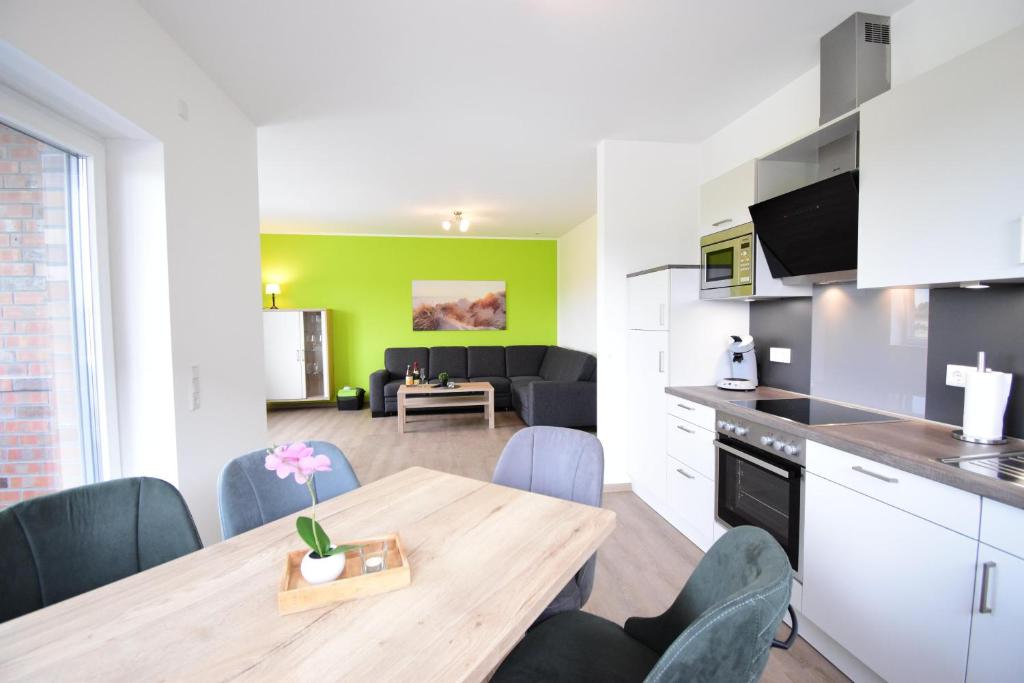 Nord Koje 5 4 في نورديش: مطبخ وغرفة معيشة مع طاولة وكراسي خشبية