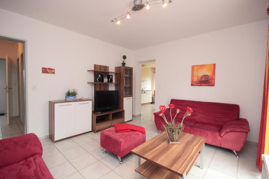 een woonkamer met een rode bank en een tafel bij Lee in Norddeich
