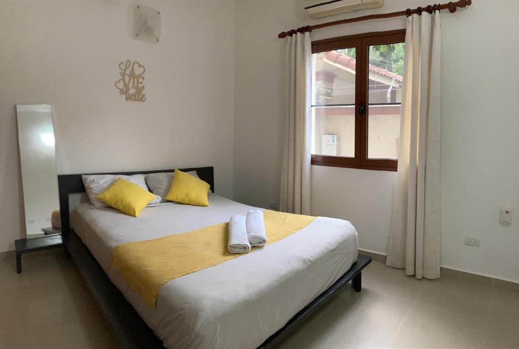 ein Schlafzimmer mit einem Bett mit gelben Kissen und einem Fenster in der Unterkunft OKAINA 2 in Cabarete