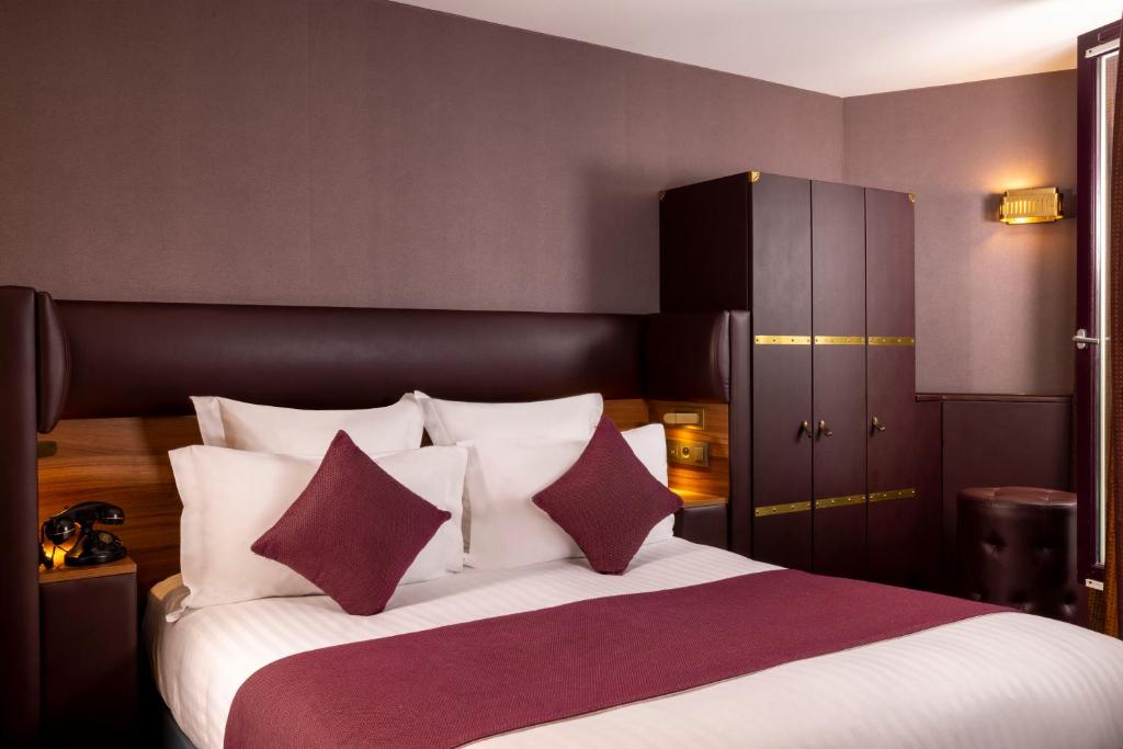 a bedroom with a large bed with red and white pillows at Hotel Whistler - Gare du Nord in Paris