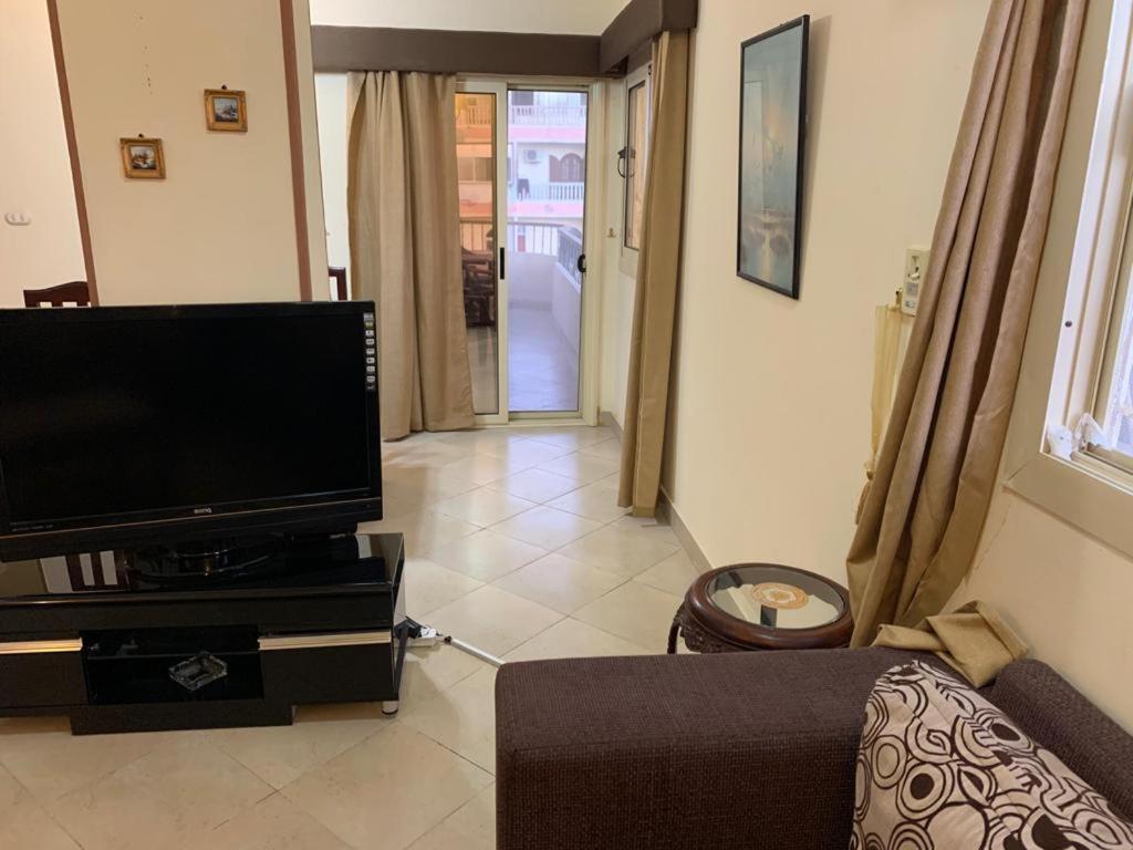 sala de estar con TV de pantalla plana y sofá en شقة عائلية راااقية ورائعة وسط الغردقة en Hurghada