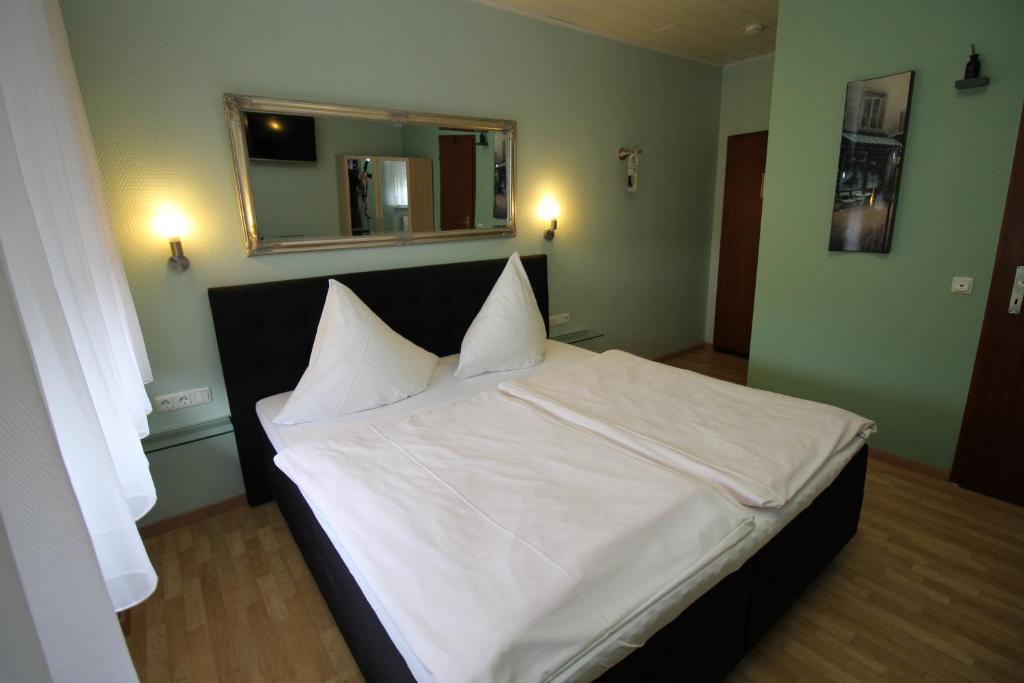 łóżko z białą pościelą i poduszkami w pokoju w obiekcie Hotel Geromont w mieście Andernach