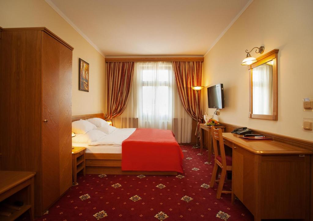 プラハにあるホテル アスカニアのベッドとデスクが備わるホテルルームです。
