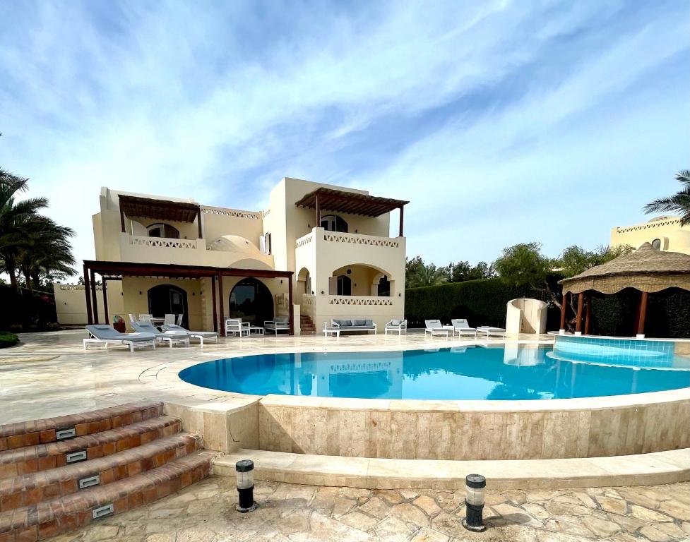 a villa with a swimming pool in front of a house at BEAUTIFUL 4-BEDROOM VILLA WITH POOL AND VIEWS OF THE LAGOON AND GOLF COURSE in Hurghada