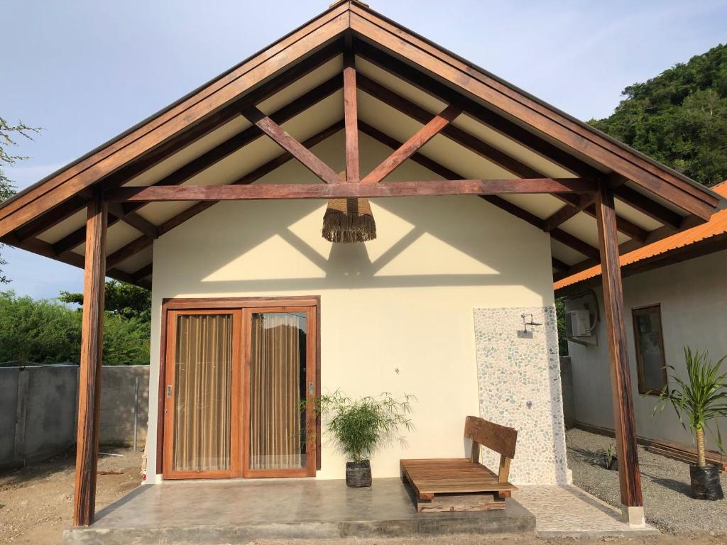 a house with a wooden roof and a bench at OUTSIDE bungalow in Sekongkang