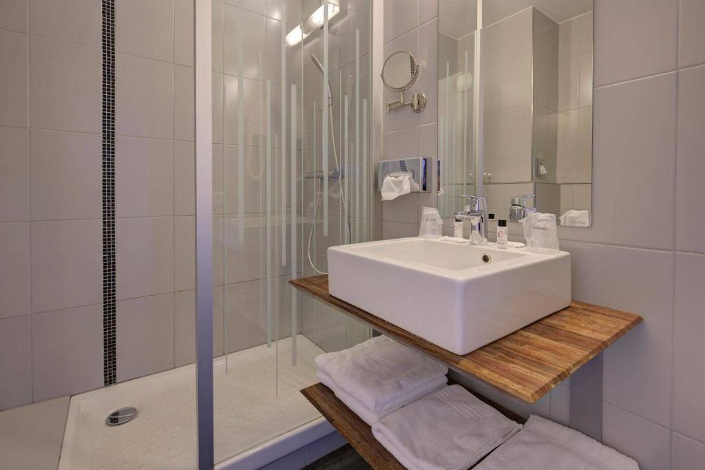 a white bathroom with a sink and a shower at Hôtel Le Nautic in Arcachon