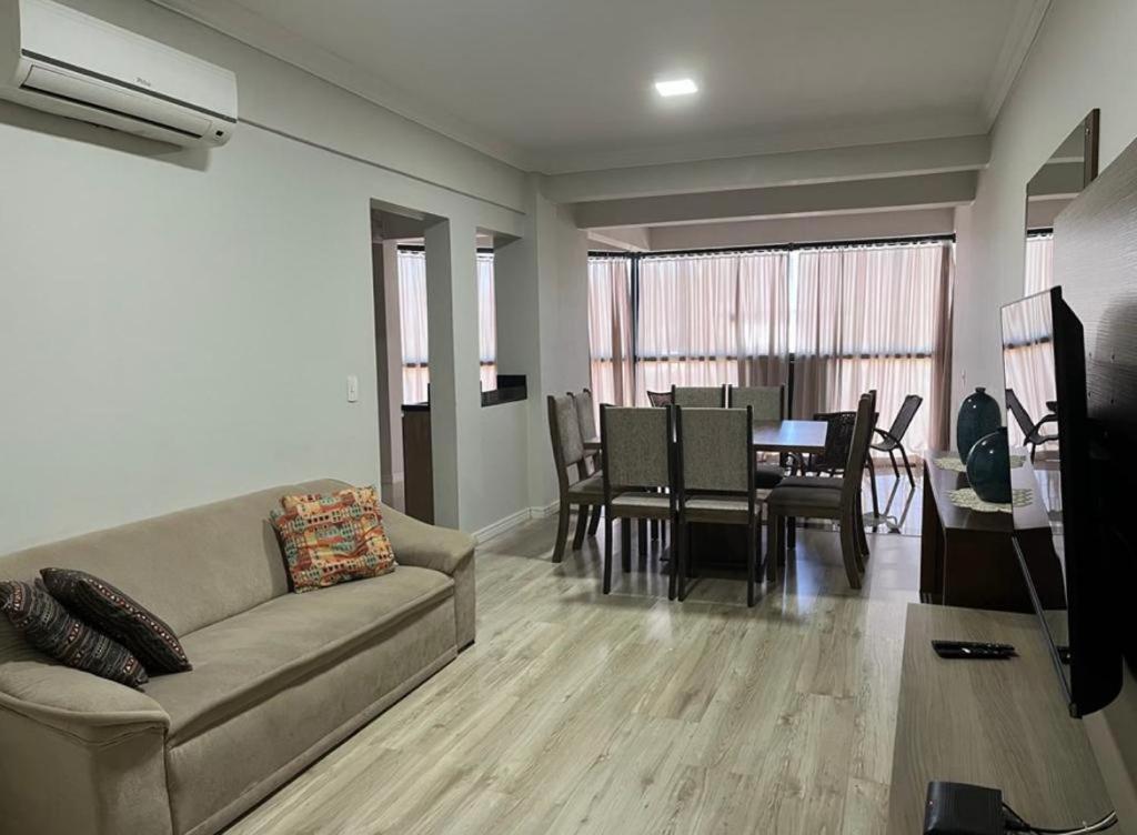 a living room with a couch and a dining room at Apartamento na Avenida próximo das Termas in Piratuba