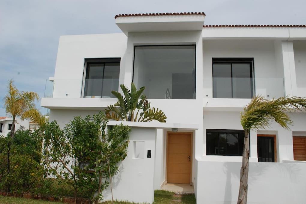 een wit huis met palmbomen ervoor bij Villa 280 m2 à Benslimane avec piscine in Aïn Sferjila