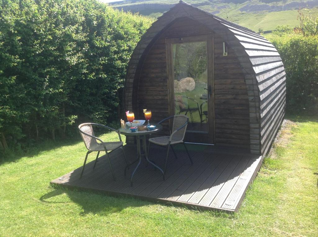 a small cabin with a table and chairs on a deck at Wharfe Camp Adults Only Glamping Pod in Kettlewell