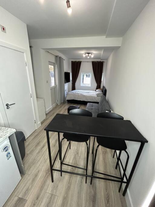 a bedroom with a table and a bed in a room at Large studio flat with garden in Teddington
