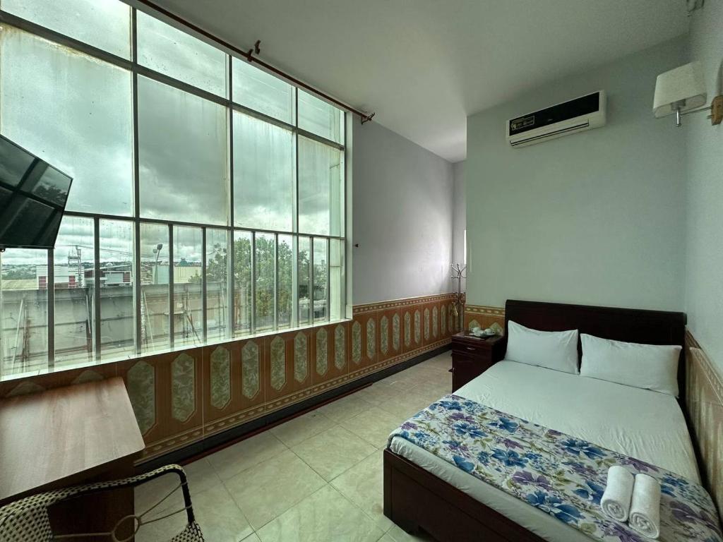 a bedroom with a bed and a large window at Tien Dat Motel in Pleiku