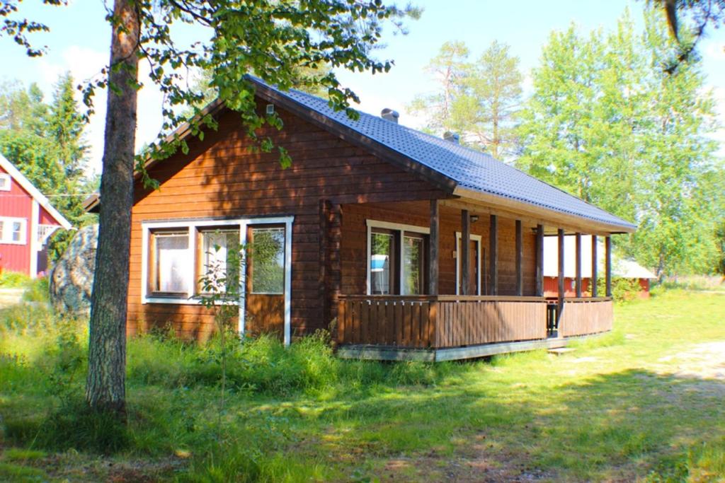 una pequeña casa de madera en un campo con un árbol en Sandsjögården Holiday Resort en Blattnicksele