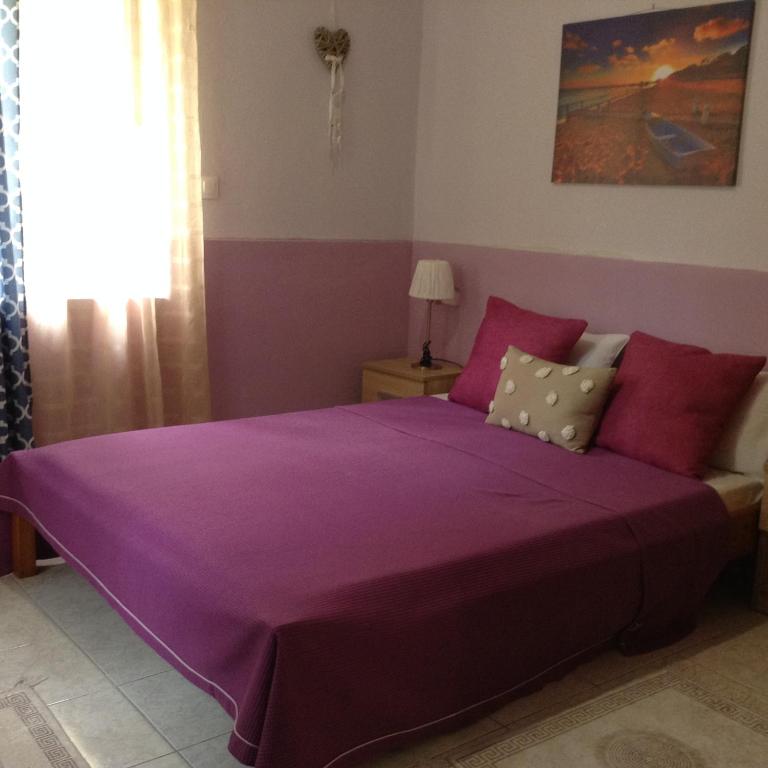 a purple bed in a room with a window at Η in Volos