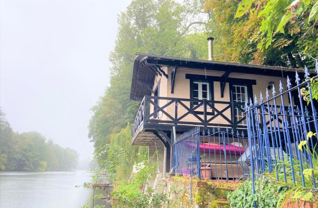 a small house on the side of a river at Le chalet bucolique au bord de l'eau in Olivet