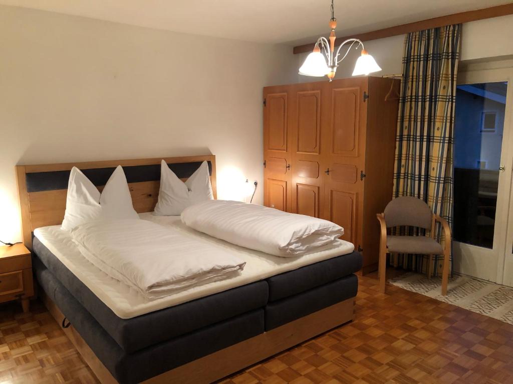a bedroom with a bed with white sheets and a chair at Villa Frieda in Zell am See