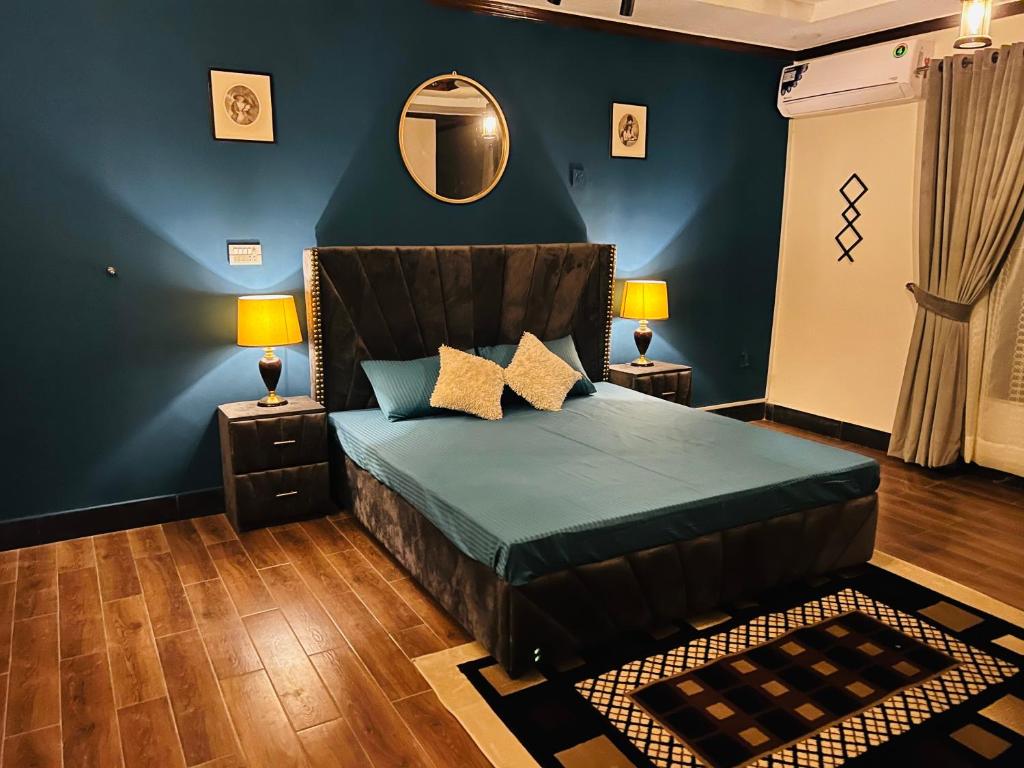 a bedroom with a bed with blue walls and a mirror at The Comfort Lodge in Islamabad