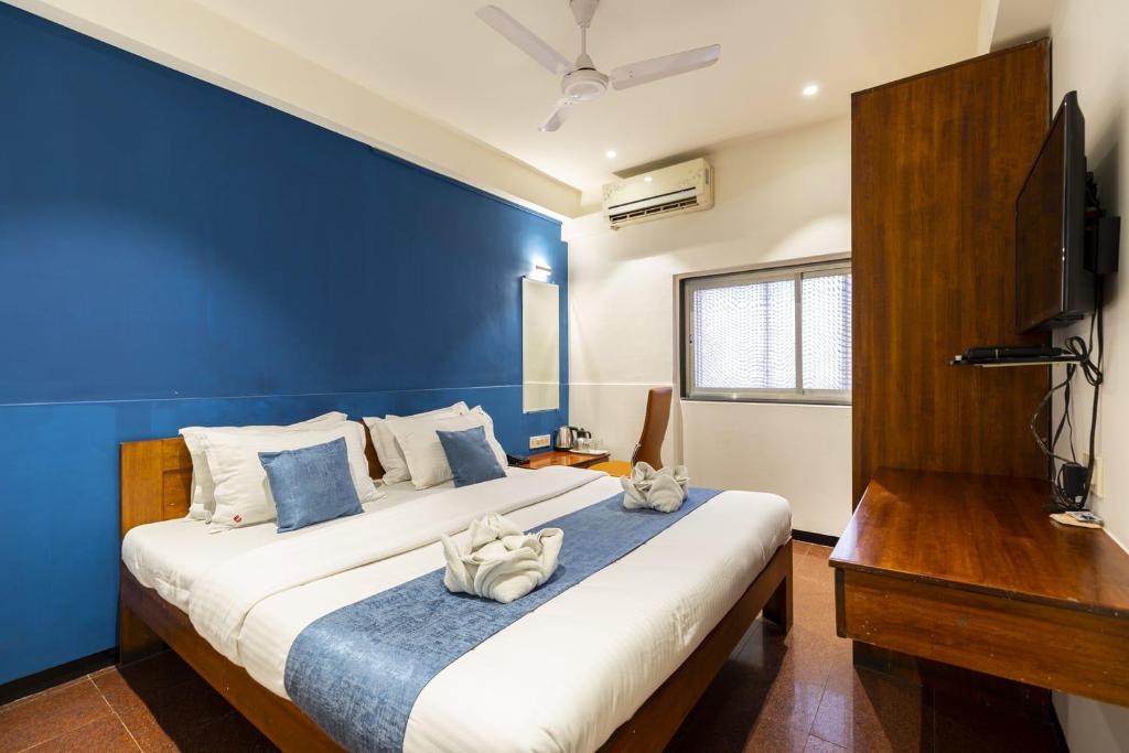a bedroom with a large bed with a blue wall at Hotel Q Deck Rooms - Vile Parle Station and Near to Mumbai Airport in Mumbai