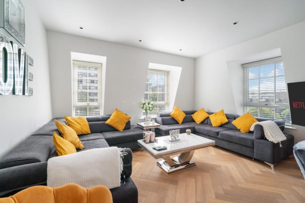 a living room with a couch and yellow pillows at Marble Arch Penthouse 3 Bed in London