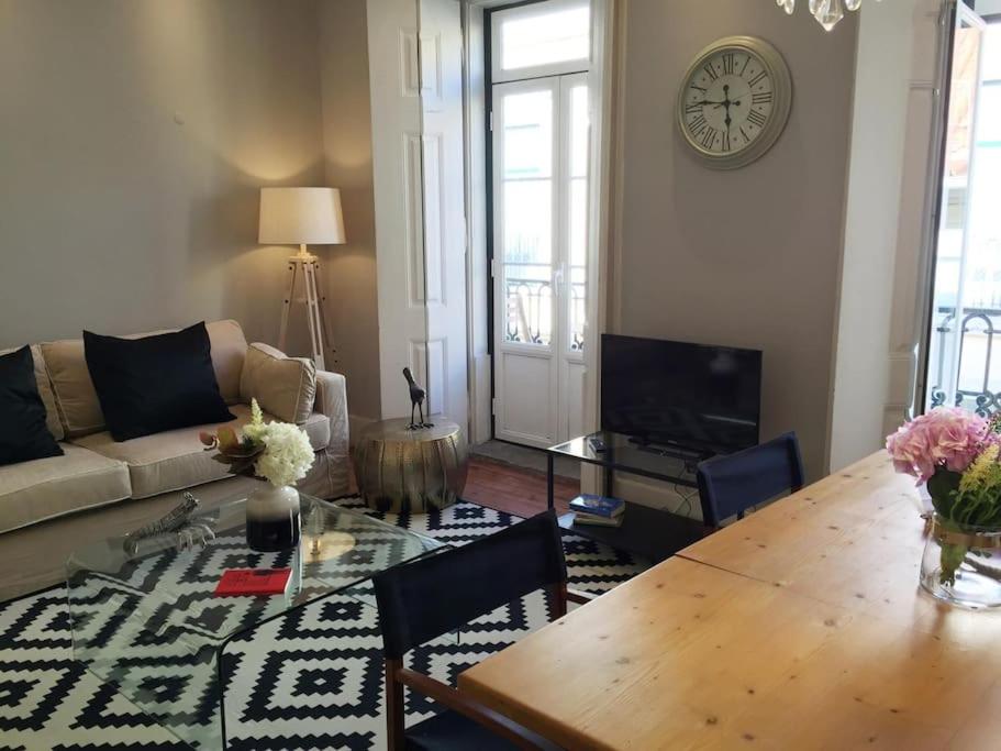 een woonkamer met een tafel en een klok aan de muur bij SM2 Romantic HOME by the gardens PR Real & Bairro Alto in Lissabon