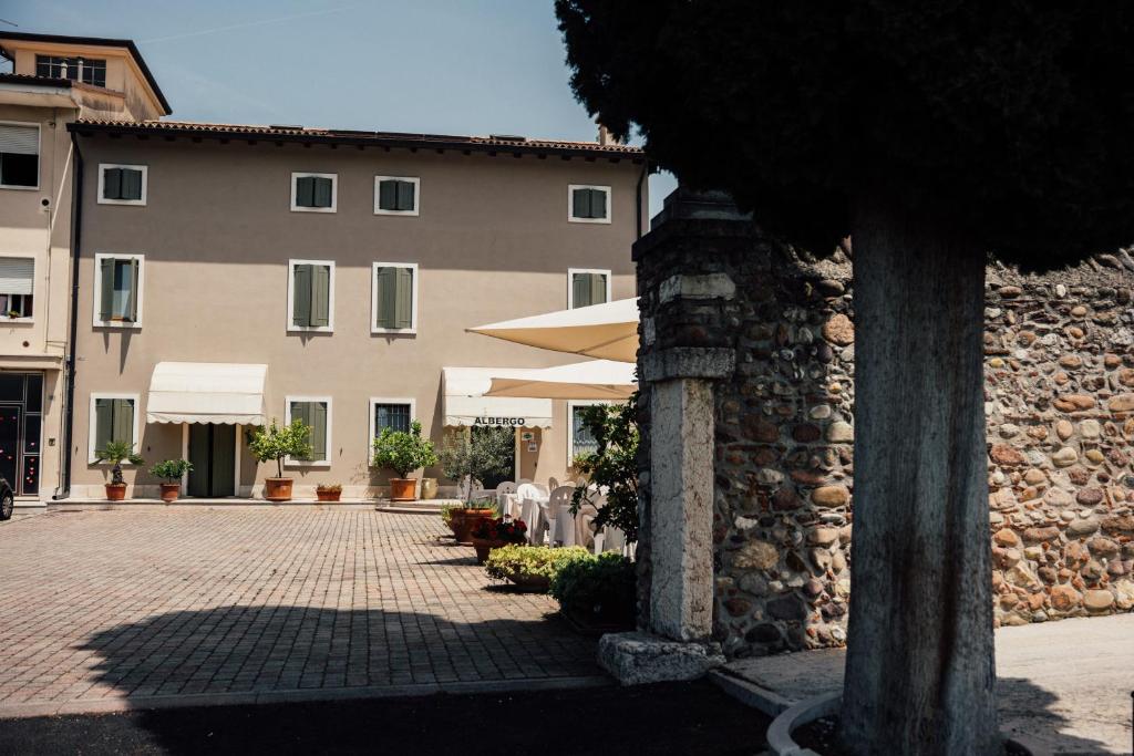 ein Gebäude mit einer Terrasse mit Tischen und Sonnenschirmen in der Unterkunft Albergo La Meridiana in Castelnuovo del Garda