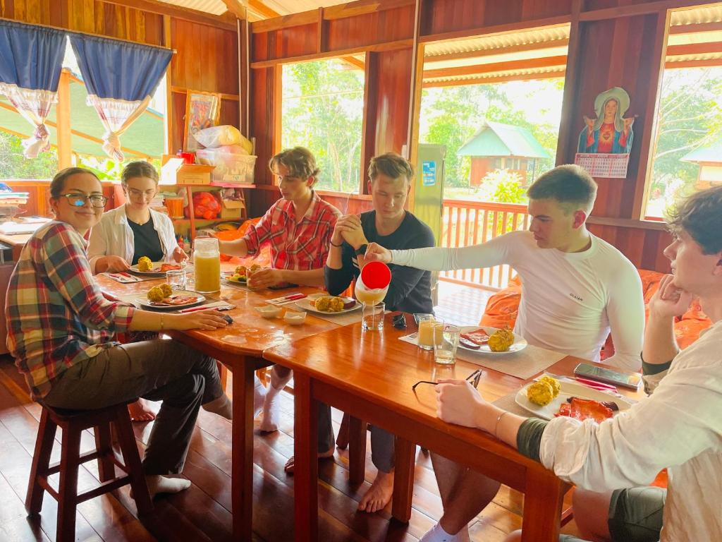 grupa ludzi siedzących przy stole jedzących jedzenie w obiekcie Sunrise of Tambopata w mieście Puerto Maldonado