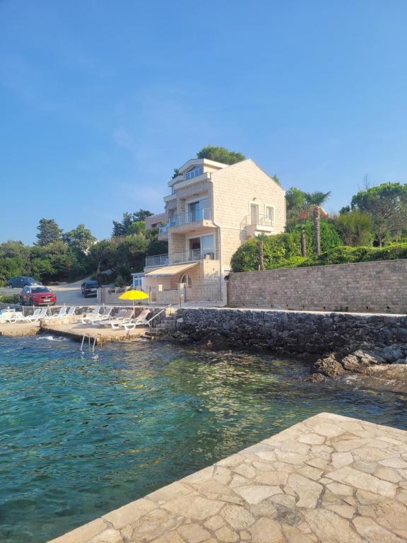 a house sitting next to a body of water at Villa Leut Montesol Tivat Krasici in Krasici