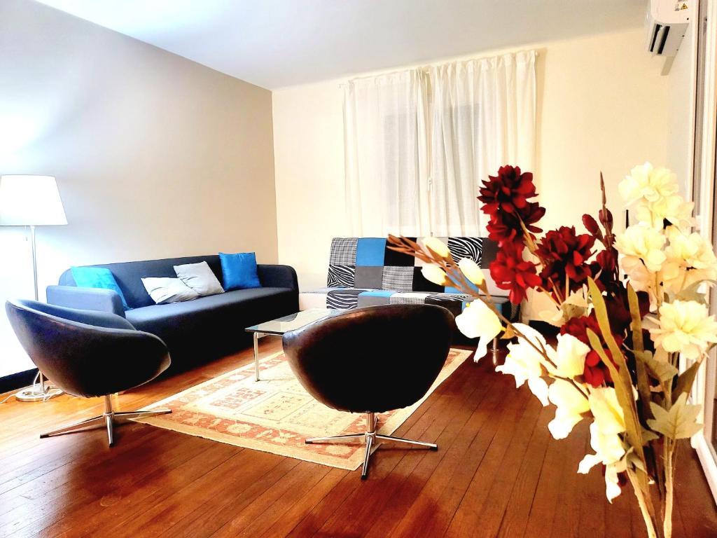 ein Wohnzimmer mit einem Sofa, Stühlen und Blumen in der Unterkunft Maison de charme in Toulouse