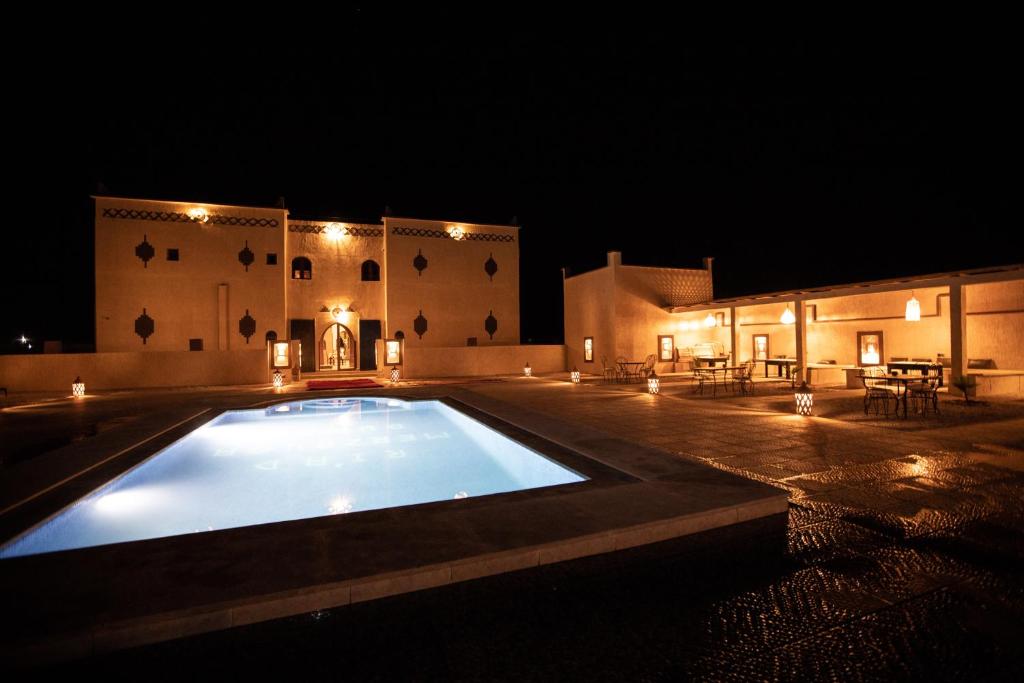 una grande piscina di fronte a un edificio di notte di Traditional Riad Merzouga Dunes a Merzouga
