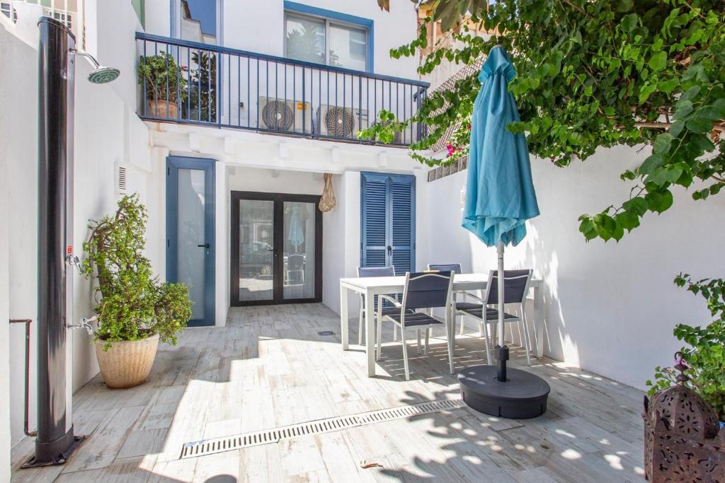 eine Terrasse mit einem Tisch und einem blauen Sonnenschirm in der Unterkunft Bluehouse Portixol in Palma de Mallorca