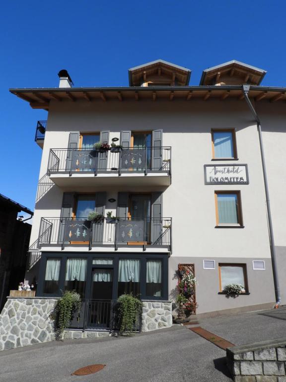 un gran edificio blanco con balcones. en Aparthotel Dolomites Living&Relax, en Commezzadura