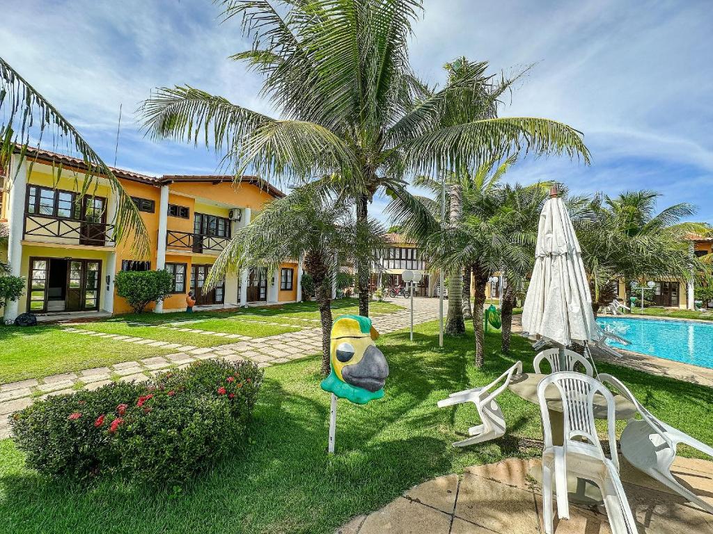 um pátio de resort com uma piscina e uma palmeira em A 200m da praia de Taperapuã, (Axé Mói) 2 suítes piscina, sauna, portaria 24hrs internet privativa 300MBPS em Porto Seguro