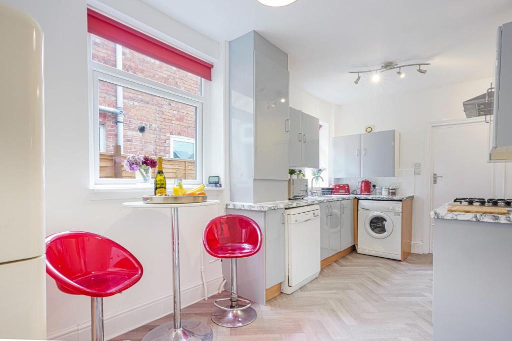 een keuken met twee rode stoelen in een kamer bij 3 Bedroom House in City Centre - Sleeps up to 7 - Free Parking, Fast Wifi, Pool Table and SmartTV with SkyTV and Netflix by Yoko Property in Northampton