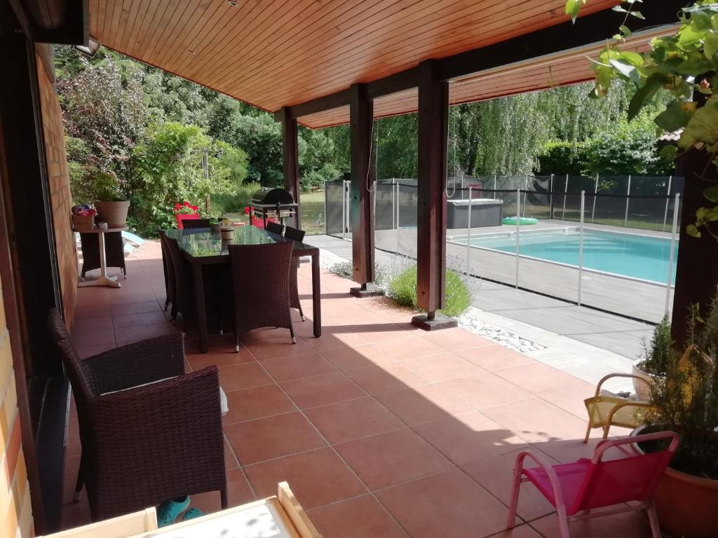 a patio with a table and chairs and a swimming pool at MagHouse in Cestas