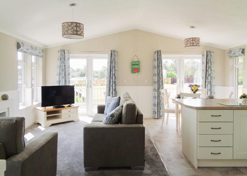 a living room with a couch and a kitchen at Otters Mead Boutique Lodges in Beetley