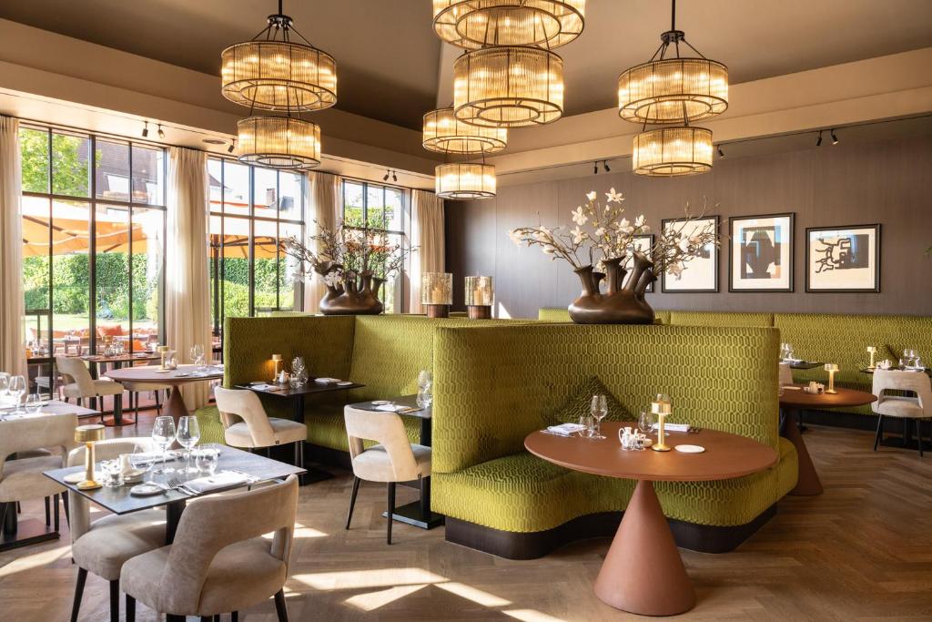 ブルージュにあるDukes' Palace Bruggeのテーブルと椅子、シャンデリアのあるレストラン