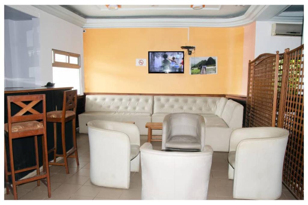 a living room with a white couch and chairs at SUP HOTEL in Douala