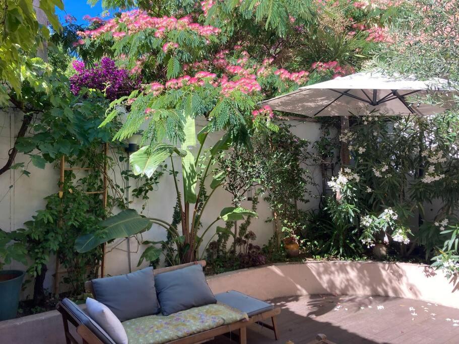 - un canapé et un parasol dans un jardin fleuri dans l'établissement Maison Montebello, à Marseille