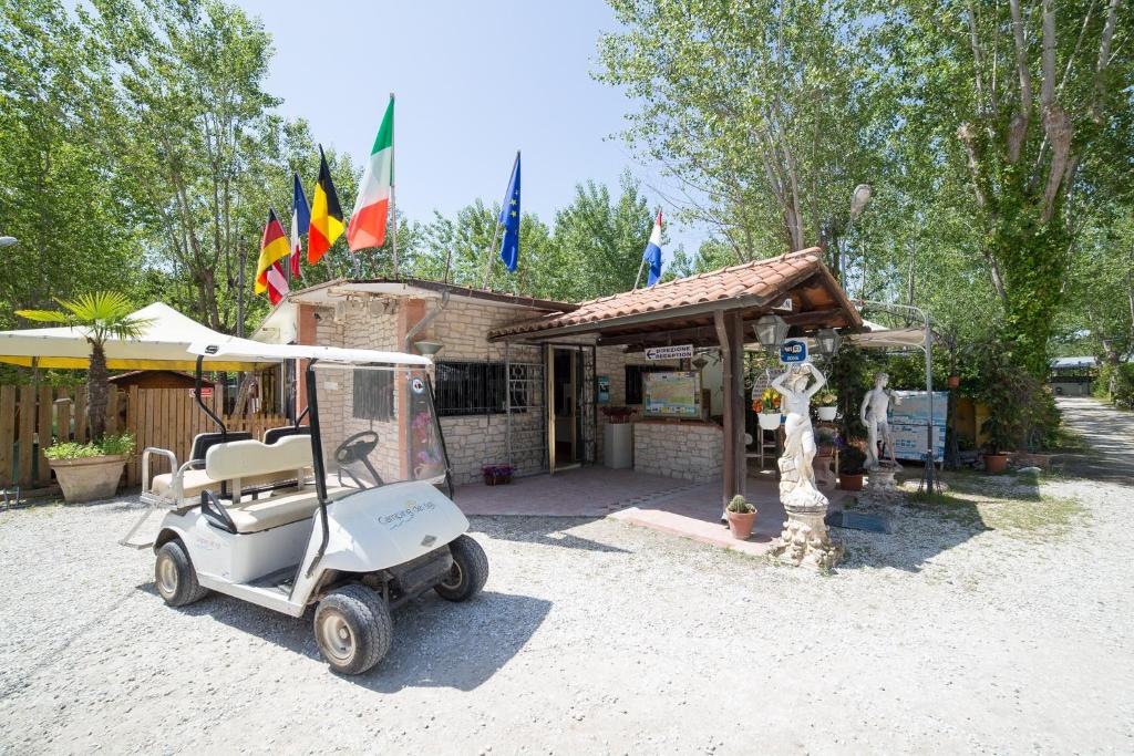 a golf cart parked in front of a building with flags at Camping dei Tigli in Torre del Lago Puccini