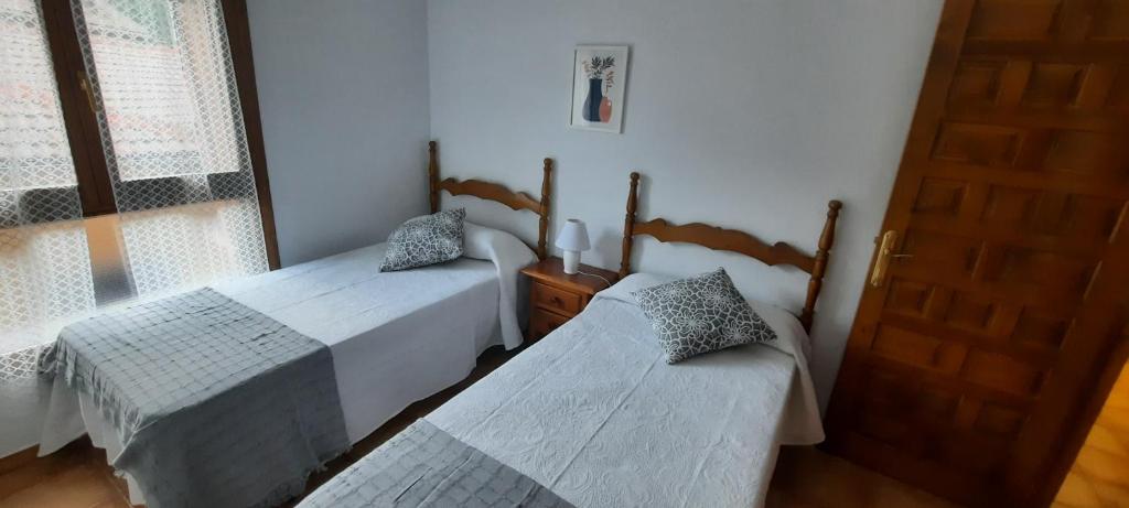 sypialnia z 2 łóżkami, drzwiami i oknem w obiekcie PLAZA centro w mieście Biescas