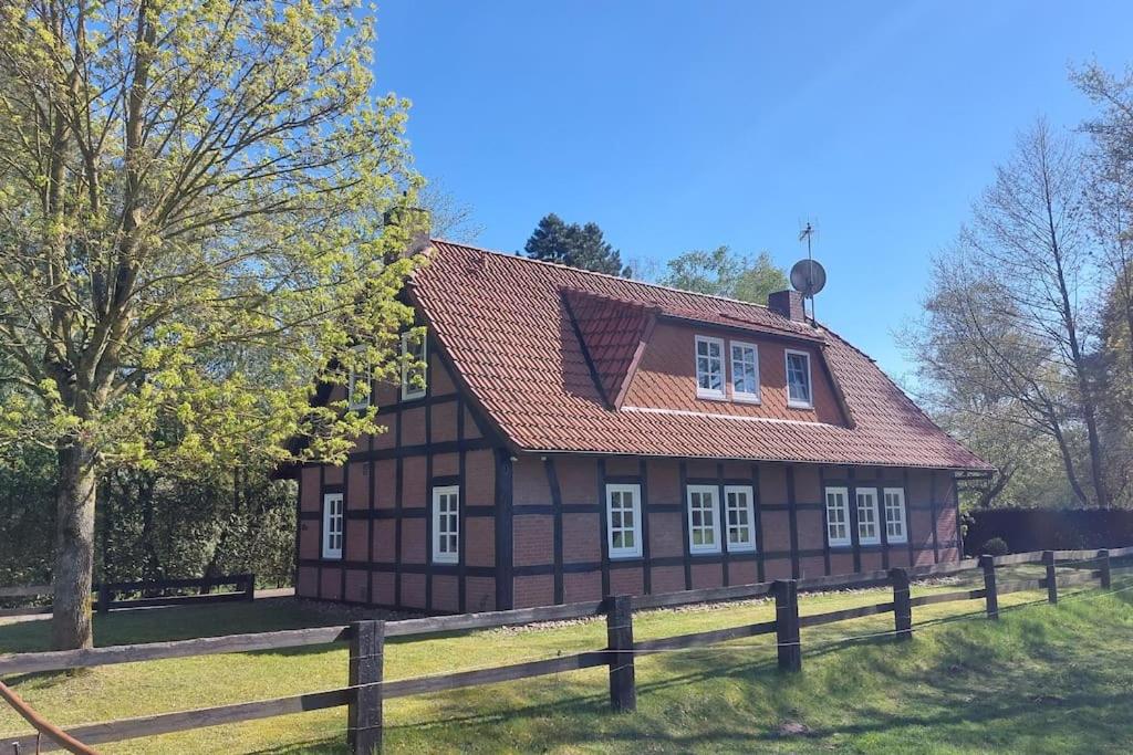 a brown house with a red roof and a fence at Das Refugium in Worpswede