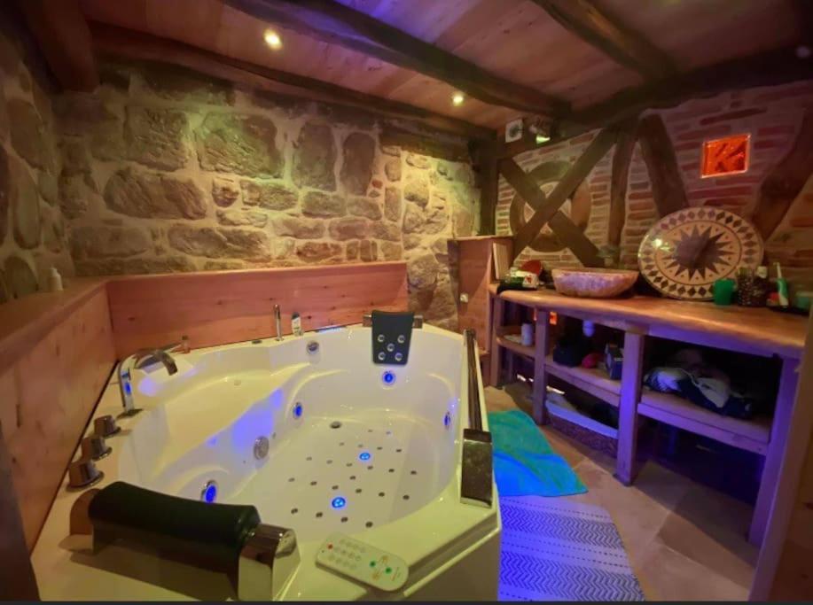 a large bath tub in a room with a stone wall at Cassiopée in Figeac