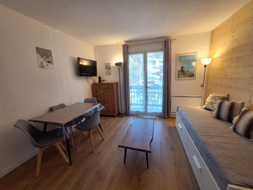 ein Wohnzimmer mit einem Bett, einem Tisch und einem Sofa in der Unterkunft Studio Les 3 Lys Auron in Auron