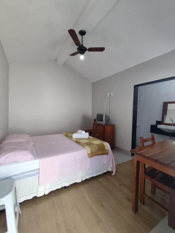 - une chambre avec un lit et un ventilateur de plafond dans l'établissement Vila da Praça Pousada, à Capitólio