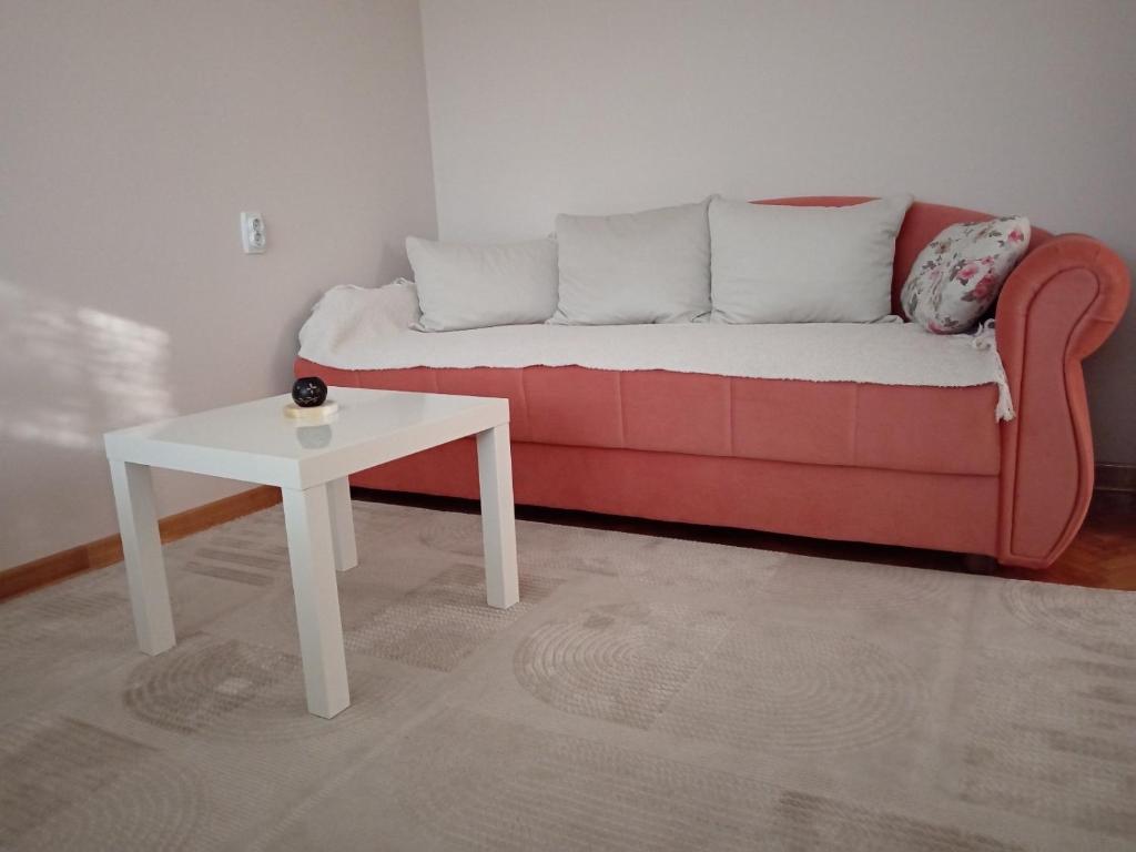 a living room with a red couch and a white table at Red Square Apartment in Pirot