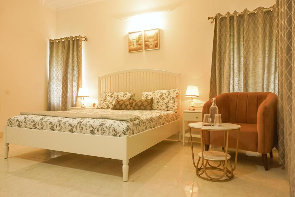a bedroom with a bed and a chair and a table at Luxre Homes - Villa in Koramangala in Bangalore